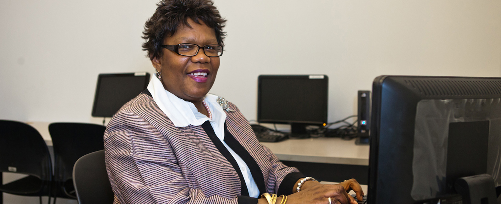 Woman in business attire sitting at a desk in a computer lab