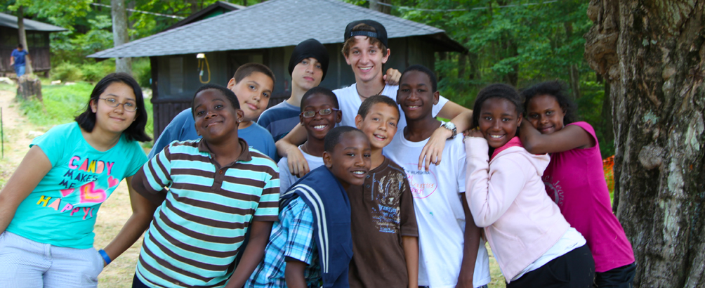 11 smiling children posing outdoors at Camp Homeward Bound.