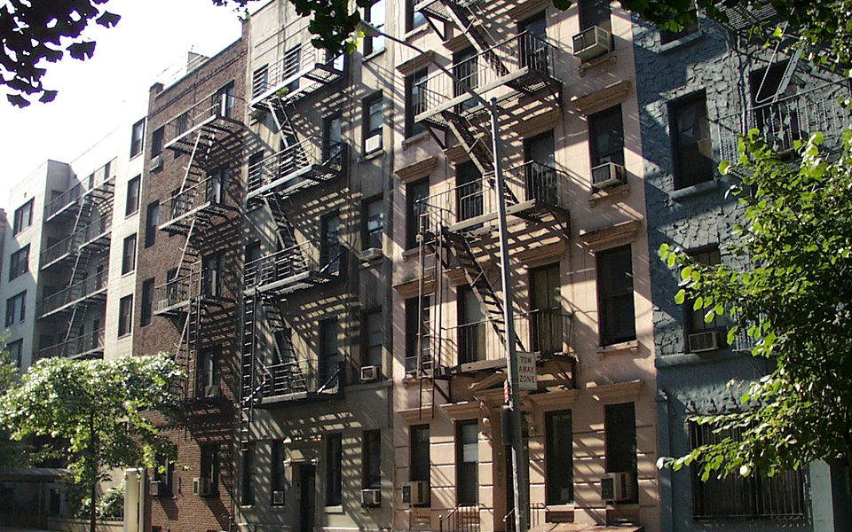 A row of brick apartment buildings surrounded by trees.