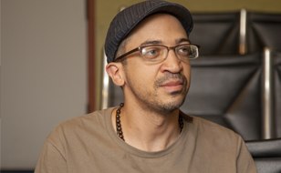 Man with brown shirt, glasses, and hat