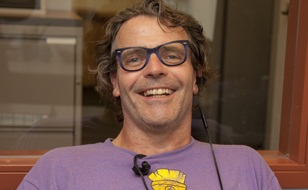 Man with purple shirt and glasses