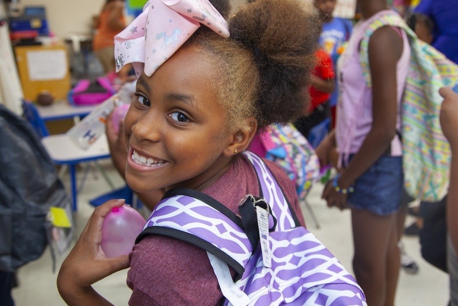 Smiling girl holding a backpack