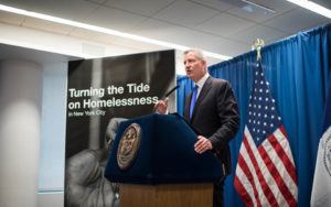 NYC Mayor Bill de Blasio speaks at a podium.