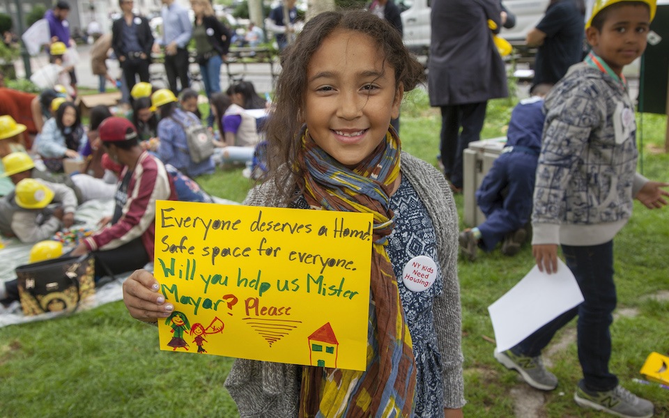 Child holding sign asking Mayor de Blasio for more housing