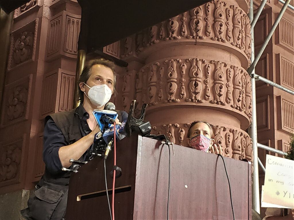 Dave Giffen stands at a podium wearing a mask