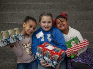 Three children holding brightly wrapped boxes