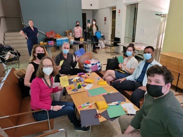 A group of people wearing face mask sitting at a table looking at the camera.