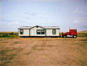 a house attached to a truck on a dirt ground