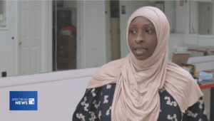 A still of a news broadcast from Spectrum News NY1 of a woman in a pink hijab talking to camera.