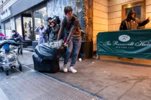 A man drags a trash bag of belongings alone the street outside of the Roosevelt Hotel