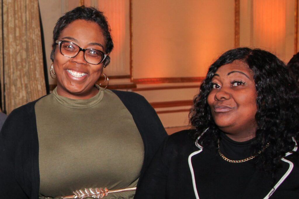 Two women standing next to each other smiling at the camera